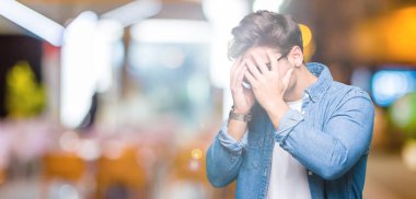 Genç yakışıklı adam üzgün ifade yüz eller ile ağlayarak süre kapsayan ile izole arka plan üzerinde güneş gözlüğü takıyor. Depresyon kavramı.