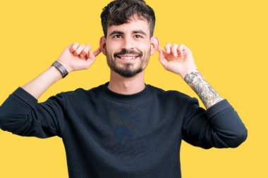 İzole arka plan gülen çekerek kulakları parmaklar, komik jest ile genç yakışıklı adam. Seçmelere sorun