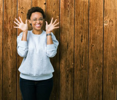 Genç güzel Afrikalı-Amerikalı kadın gözlük gösterilen ve parmakları ile işaret izole arka plan üzerinde number ten kendinden emin ve mutlu gülümseyerek süre.