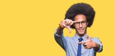 Elle yapma çerçeve ve parmakları ile mutlu yüz gülümseyen gözlüklü afro saçlı genç Afro-Amerikalı iş adamı. Yaratıcılık ve Fotoğrafçılık kavramı.