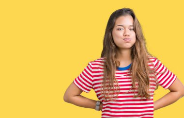 Komik surat ile yanakları şişirme izole arka plan üzerinde tişört giyen genç güzel esmer kadın çizgili. Ağız ile hava, deli ifade şişirilmiş.