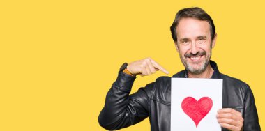 Yakışıklı orta yaş adam sürpriz yüz kendini işaret parmak ile kırmızı kalp ile kağıt tutarak