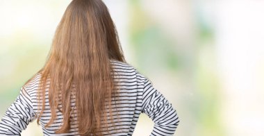 Genç güzel esmer kadın geriye doğru vücut üzerinde kollar ile bakıyor izole arka planda çizgili kazak giyiyor