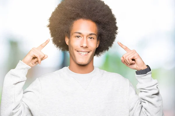 Joven Afroamericano Con Cabello Afro Usando Sudadera Deportiva Sonriendo Señalando —  Fotos de Stock