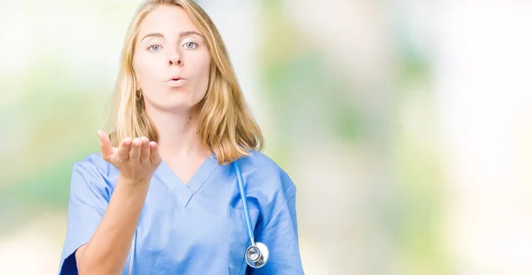 オンエアされて素敵なセクシーな手でキスを吹いてカメラ目線孤立の背景に医療制服を着て美しい若い医者の女性 愛情表現 — ストック写真