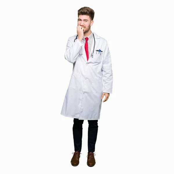 不安や両手の爪を噛んで口の中で緊張を探して医療のコートを着ている若いハンサムな医者の男 不安の問題 — ストック写真