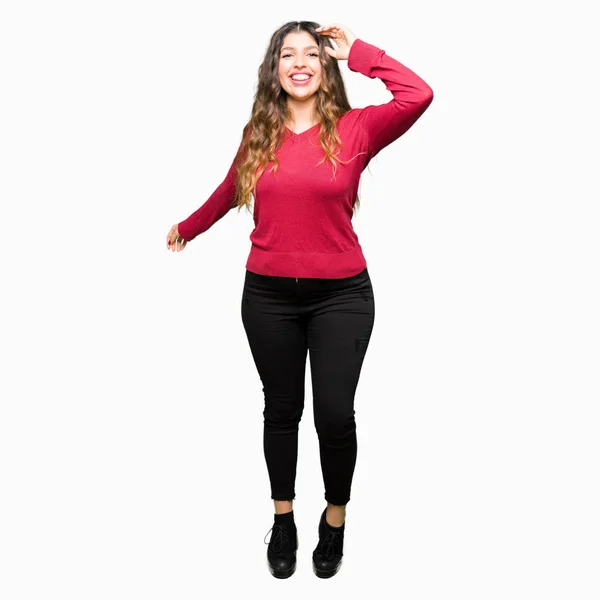 カジュアルなと自信を持って音楽を聴いて移動笑みを浮かべて赤いセーター踊る幸せで陽気な身に着けている若い美しい女性 — ストック写真