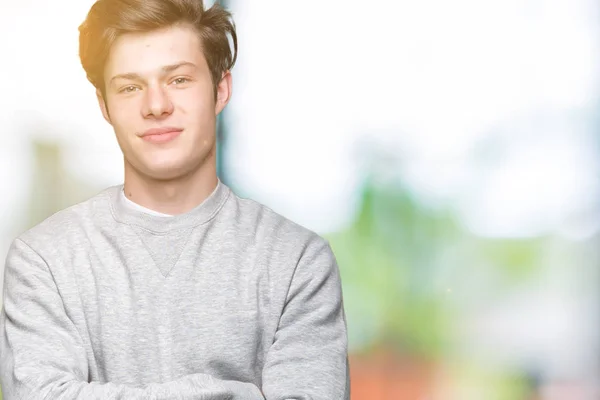 Young handsome sporty man wearing sweatshirt over isolated background happy face smiling with crossed arms looking at the camera. Positive person.