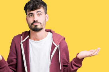 İzole arka plan clueless ve şaşkın bir ifadeyle kollar ve eller kaldırdı genç yakışıklı adam. Şüphe kavramı.