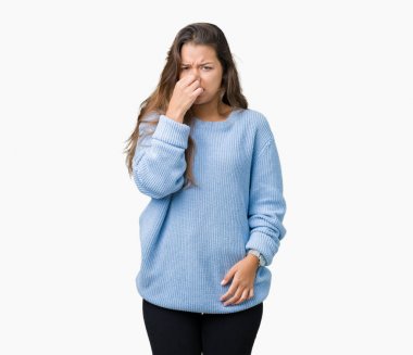 İzole arka plan kokulu üzerinde mavi kış kazak pis ve iğrenç bir şey, dayanılmaz koku, holding nefes parmak ile burun üzerinde giyen genç güzel esmer kadın. Kötü kokuyor kavramı.