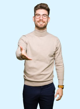 Tebrik ve konuksever dost sunan karşılıklı gülümseyen gözlüklü genç yakışıklı iş adamı. Başarılı iş.