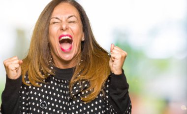 Moda ceket giyen güzel orta yaş kadın silah ile başarı için deli ve çılgın kutluyor ve heyecanlı çığlık kapalı gözleri kaldırdı. Kazanan kavramı