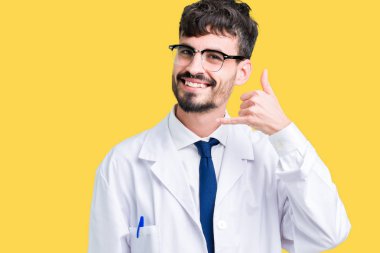 İşin gülümseyen izole arka plan üzerinde beyaz önlük giyen genç profesyonel bilim adamı telefon hareketi ile el ve parmak telefonda konuşuyor gibi. Kavramları iletişim.