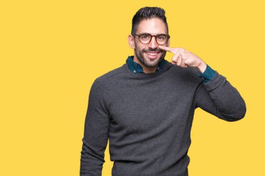 Genç yakışıklı adam gözlük izole üzerinde işaretleme için yüz ve burun, neşeli gülümseyerek el parmak ile arka plan