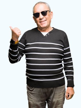 Kış kazak ve seyir ve başparmak yanında yukarıyı mutlu yüz ile gülümseyen güneş gözlüğü takan yakışıklı komuta sizde.