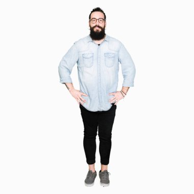 Uzun saç ve sakal gevşek ciddi ifade ile yüzünde gözlüklü genç hipster adam. Basit ve doğal kameraya bakıyor.