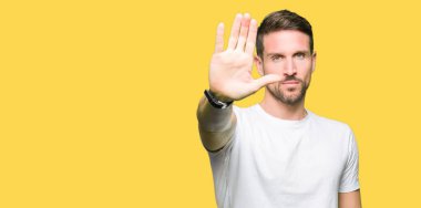 Yakışıklı adam rahat beyaz t-shirt giyen elin avuç ile şarkı stop yapıyor. Negatif ve ciddi bir jest yüz ifadesiyle uyarı.