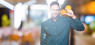 Genç yakışıklı iş adamı izole arka plan gülümseyen ve boyutu işaret parmaklı ararken ve kamera işi el ile kendinden emin eller üzerinde gözlük takıyorum. Ölçü kavramı.