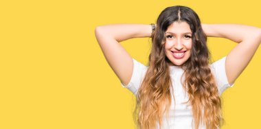 Genç güzel kadın rahat beyaz t-shirt giyen rahatlatıcı ve kollar ve eller baş ve boyun arkasında germe, mutlu gülümseyen