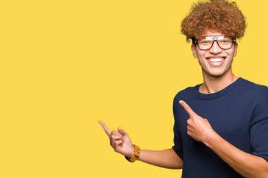 Afro gülümseyen ve iki elleri ve parmakları ile tarafına işaret kamera bakarak gözlüklü genç yakışıklı adamla.