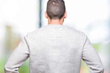 İzole arka plan ayakta geriye doğru uzakta silah ile vücut üzerinde seyir üzerinde sweatshirt giyen genç yakışıklı adam