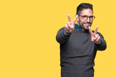 Zafer işareti yapıyor parmak gösterilen kamera seyir gülümseyen izole arka plan üzerinde gözlük takan yakışıklı delikanlı. İki numaralı.