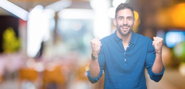 İzole arka plan kutlama üzerinde genç yakışıklı adam şaşırttı ve başarı için kaldırdı kollarını açarak hayret ve gözleri açık. Kazanan kavramı.