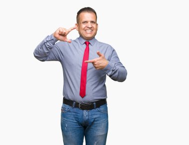 Orta yaş Arap adam elleriyle yapım çerçeve ve parmakları ile mutlu yüz gülümseyen izole arka plan üzerinde kırmızı kravat takıyor. Yaratıcılık ve Fotoğrafçılık kavramı.