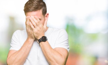 Yakışıklı adam üzgün ifadeyle yüz eller ile ağlayarak süre kapsayan Casual beyaz t-shirt giyiyor. Depresyon kavramı.