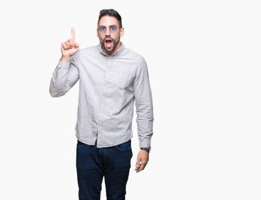 Genç yakışıklı adam başarılı fikirle izole arka plan işaret parmağı üzerinde güneş gözlüğü takıyor. Çıktıktan ve mutlu. Bir numara.