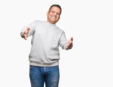 Orta yaş Arap adam sarılmak için kollarını açarak gülümseyerek kameraya bakarak izole arka plan üzerinde spor kazak giyiyor. Neşeli ifade kucaklayan mutluluk.