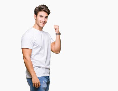 Seyir ve başparmak yanında yukarıyı mutlu yüz ile gülümseyen izole arka plan üzerinde beyaz t-shirt giyen genç yakışıklı adam.