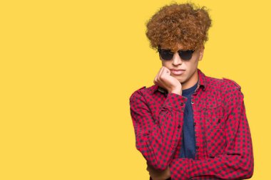 Yakışıklı genç afro saçlı stresli ve gergin elle çivi ısırma ağzına bakarak güneş gözlüğü takıyor. Anksiyete sorunu.