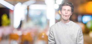 İzole arka plan yapma balık yüzüne dudaklı, çılgın ve komik bir jest sweatshirt giyen genç yakışıklı sportif adam. Komik ifade.