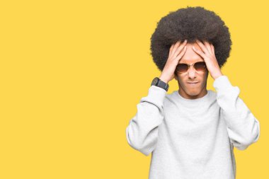 Afrikalı-Amerikalı genç afro saçlı giyen güneş gözlüğü çünkü umutsuz ve stresli baş ağrısı acı acı ve Migren. Ellerini kafasına.