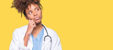Genç Afro-Amerikan doktor kadın elle çene düşünme hakkında soru, dalgın ifade izole arka plan yüzünden. Düşünceli yüzüyle gülümsüyor. Şüphe kavramı.