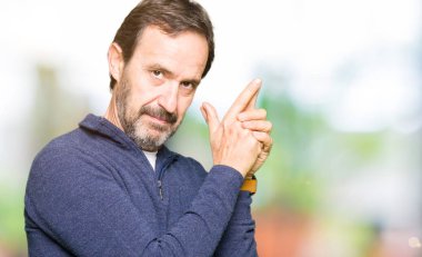 El hareketi ile sembolik silah tutan, çekim silah, kızgın yüz öldürmek oynamaya bir kazak giyen orta yaş yakışıklı adam