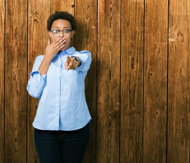 Genç güzel Afro-Amerikan iş kadını izole üzerinde arka plan sizin parmak el kamerasıyla ağzına, utanç ifadesi işaret eden gülme