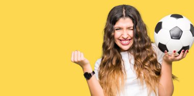 Genç yetişkin kadın futbol topu tutan gurur çığlık ve zafer ve başarı çok heyecanlı kutluyor, duygu tezahürat