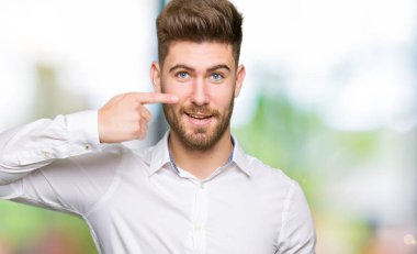 Genç yakışıklı iş yüz ve burun, neşeli gülümseyerek el parmak ile işaret dostum
