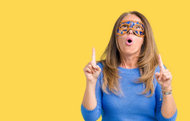 Venedik karnaval maskesi izole arka plan üzerinde giyen güzel orta yaş kadın hayrete ve yukarıya bakıyor ve parmakları ile işaret ve silah kaldırdı şaşırttı.