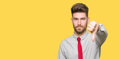 Mutsuz ve kızgın ret gösterilen ve başparmak aşağı hareketi ile negatif görünümlü genç yakışıklı iş adamı. Kötü ifade.