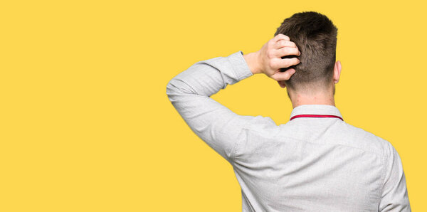 Молодой привлекательный бизнесмен задом наперед думает о сомнениях с поднятой головой
