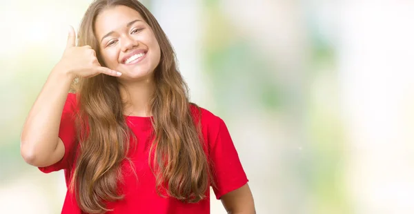 赤いTシャツを着た若い美しいブルネットの女性は 電話で話すような手と指で電話ジェスチャーをして微笑んでいます 概念の伝達 — ストック写真