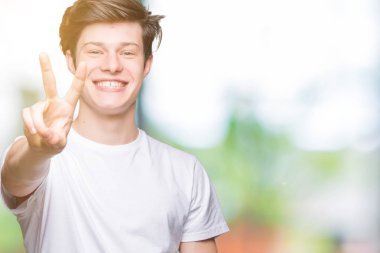 Yakışıklı delikanlı gösterilen ve parmakları ile işaret izole arka plan üzerinde rahat beyaz t-shirt giyen ikincisi ise kendinden emin ve mutlu gülümseyerek.