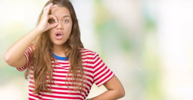 Genç güzel esmer kadın izole arka plan üzerinde çizgili t-shirt giyen sürpriz yüz, göz parmaklarıyla bakarak şok ok jest yapıyor. İnanılmaz ifade.