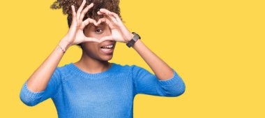 İzole arka plan yaparken kalp şekli ile el ve parmak işareti seyir gülümseyen güzel genç Afro-Amerikan kadın