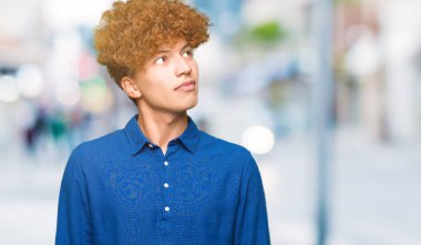 Afro saç ile genç yakışıklı zarif adam görünümlü yan ve bakmak uzağa düşünme gülümsüyor.