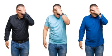 Mahcup ifadeyle parmaklarımın arasından bakan Arap orta yaş adam yüz ve gözler el ile kapsayan şok bakmak izole arka plan üzerinde bileşimi.