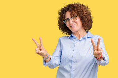 Güzel orta ager üst düzey businees kadın parmaklarını zafer işareti yaparken gösterilen kamera seyir gülümseyen izole arka plan üzerinde gözlük takıyorum. İki numaralı.